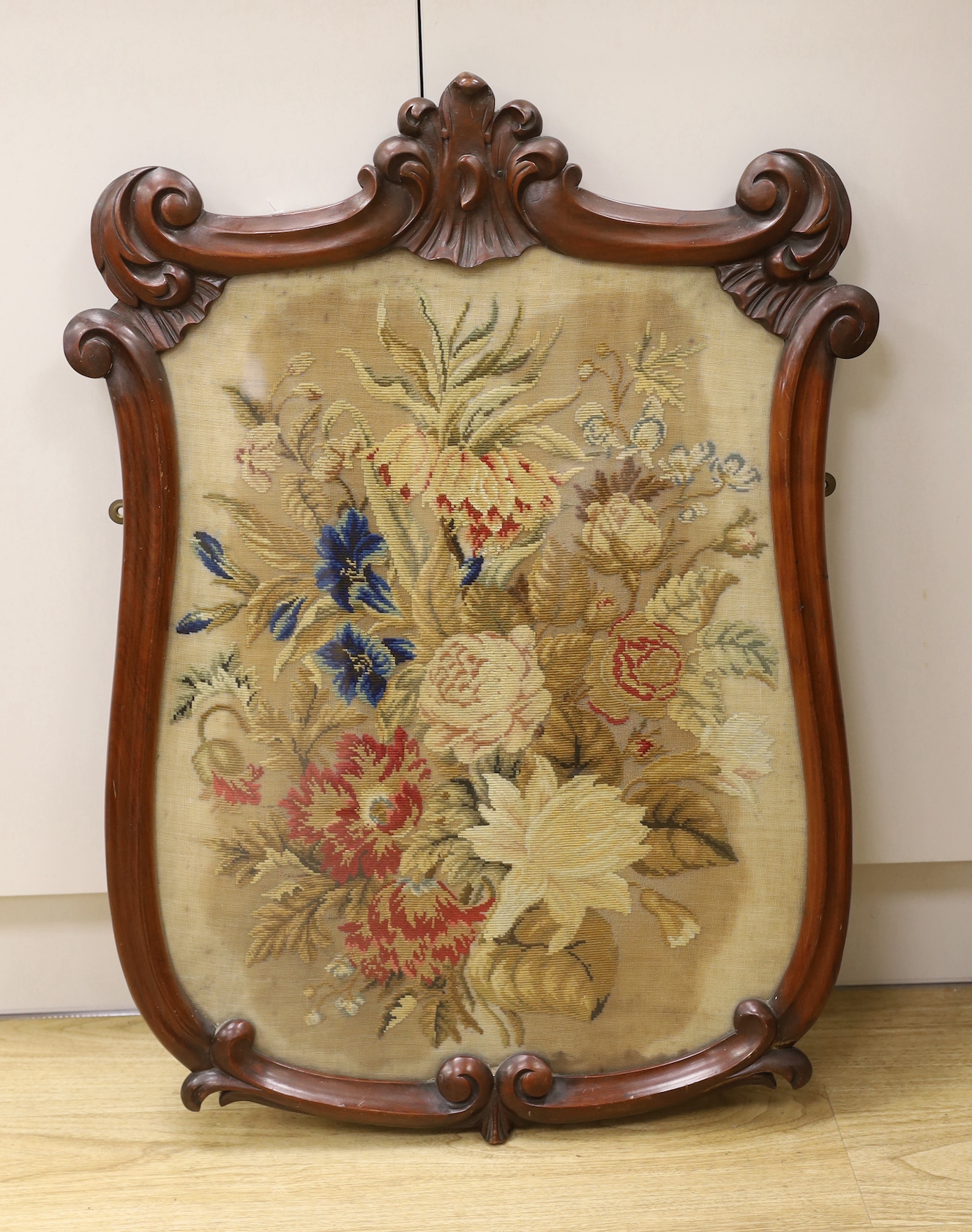 A Victorian petite point embroidered panel, in shield shaped mahogany frame (ex pole screen), 80cm high, 56cm wide